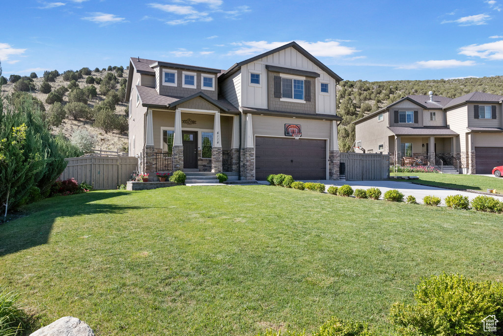 Craftsman-style home with board and batten siding, an attached garage, driveway, and stone siding