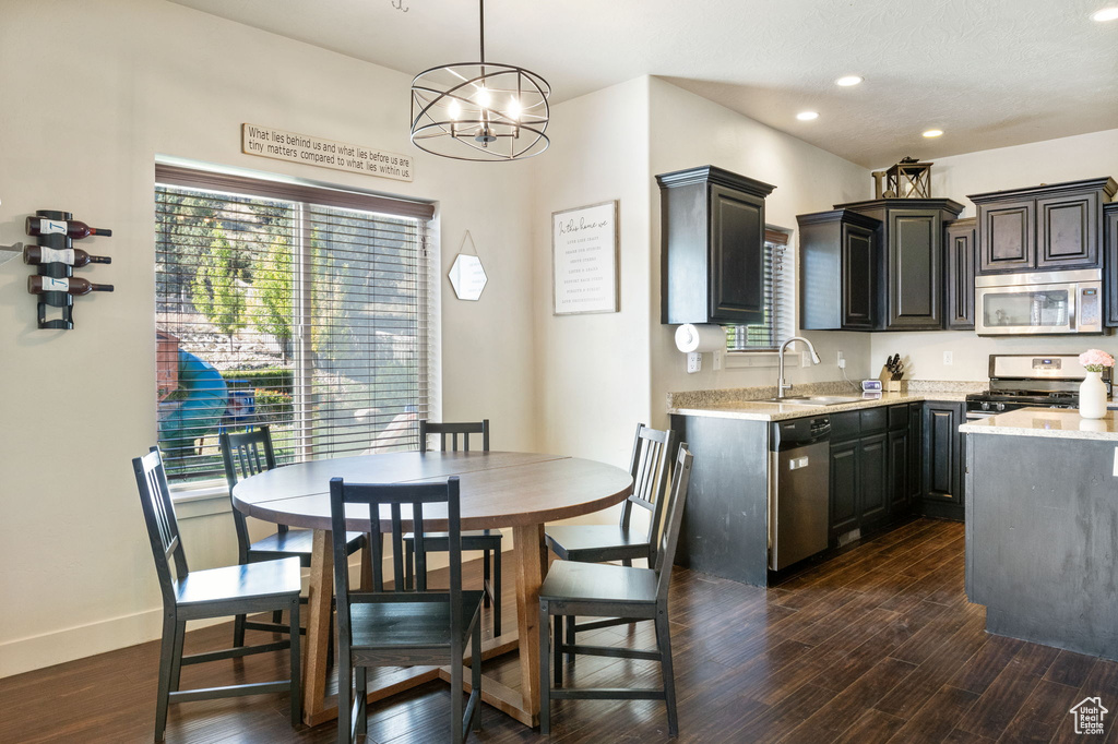 Kitchen with appliances with stainless steel finishes, a sink, dark wood finished floors, recessed lighting, and a chandelier