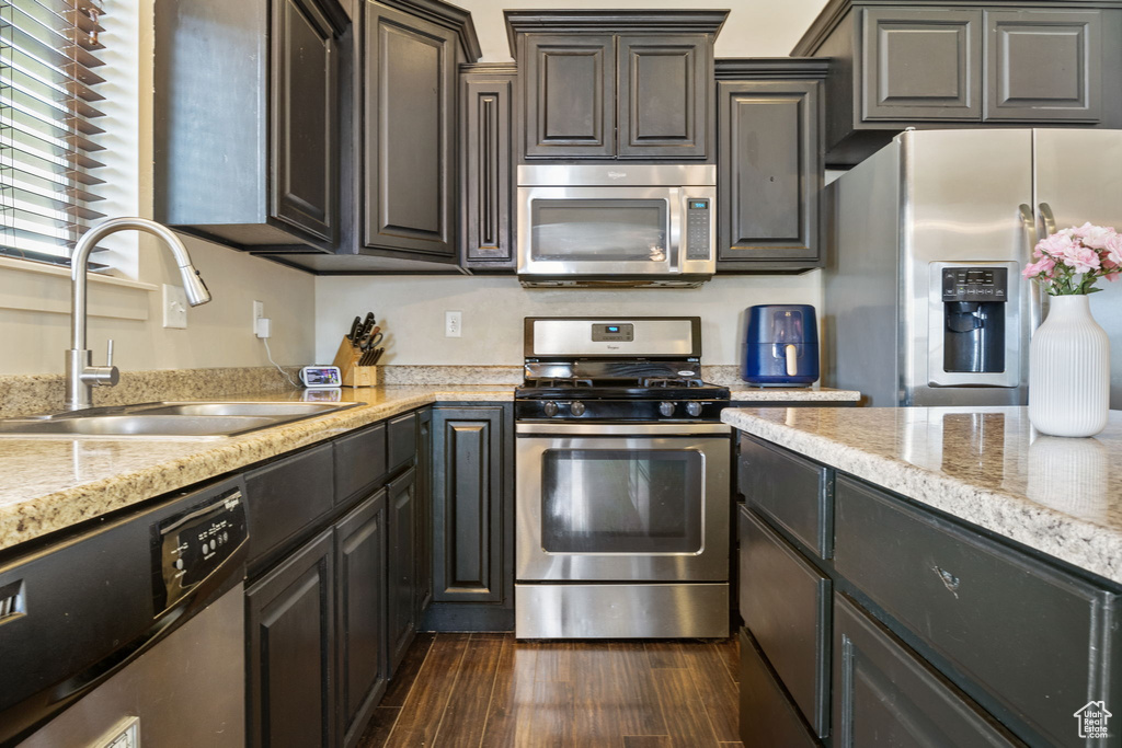 Kitchen with stainless steel appliances, a sink, and dark wood-style floors