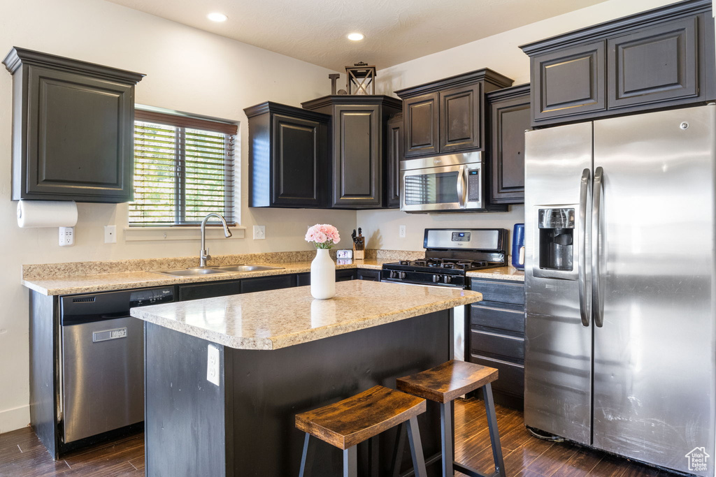 Kitchen featuring stainless steel appliances, a sink, dark wood-style flooring, a kitchen island, and recessed lighting