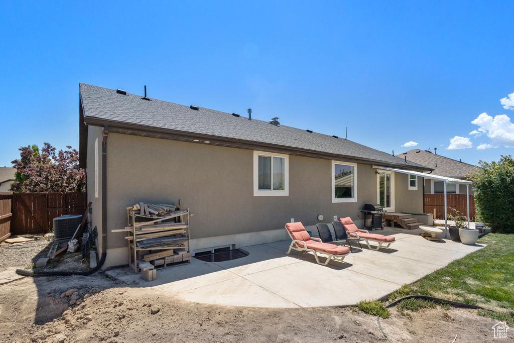 Rear view of property featuring a patio, stucco siding, central AC, and a shingled roof