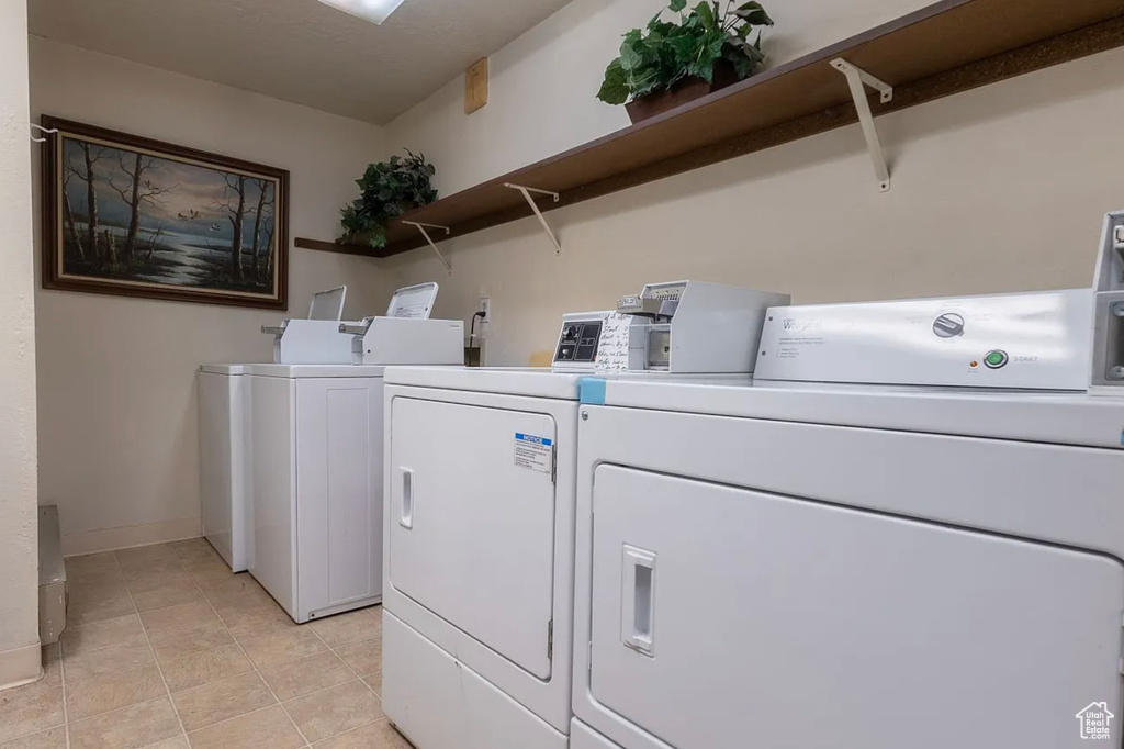 Shared laundry room with washing machine and clothes dryer, light tile patterned floors, and baseboards