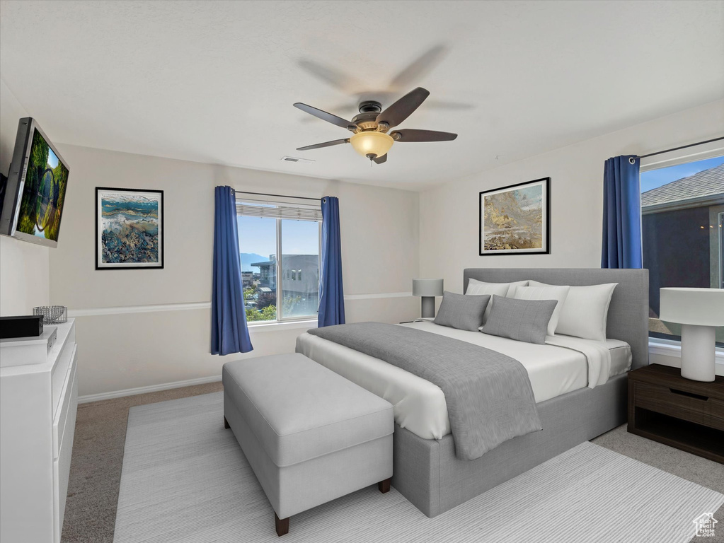 Bedroom with light colored carpet, baseboards, and ceiling fan