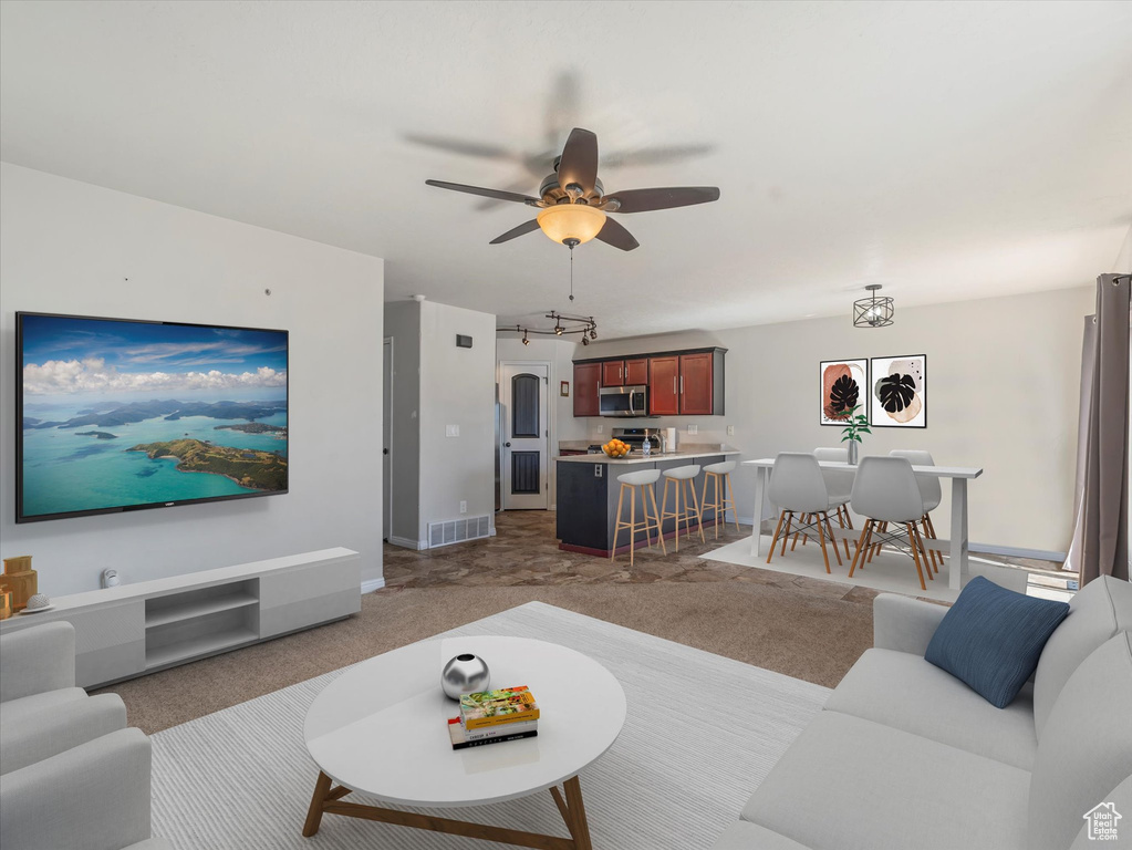 Carpeted living area with ceiling fan and baseboards