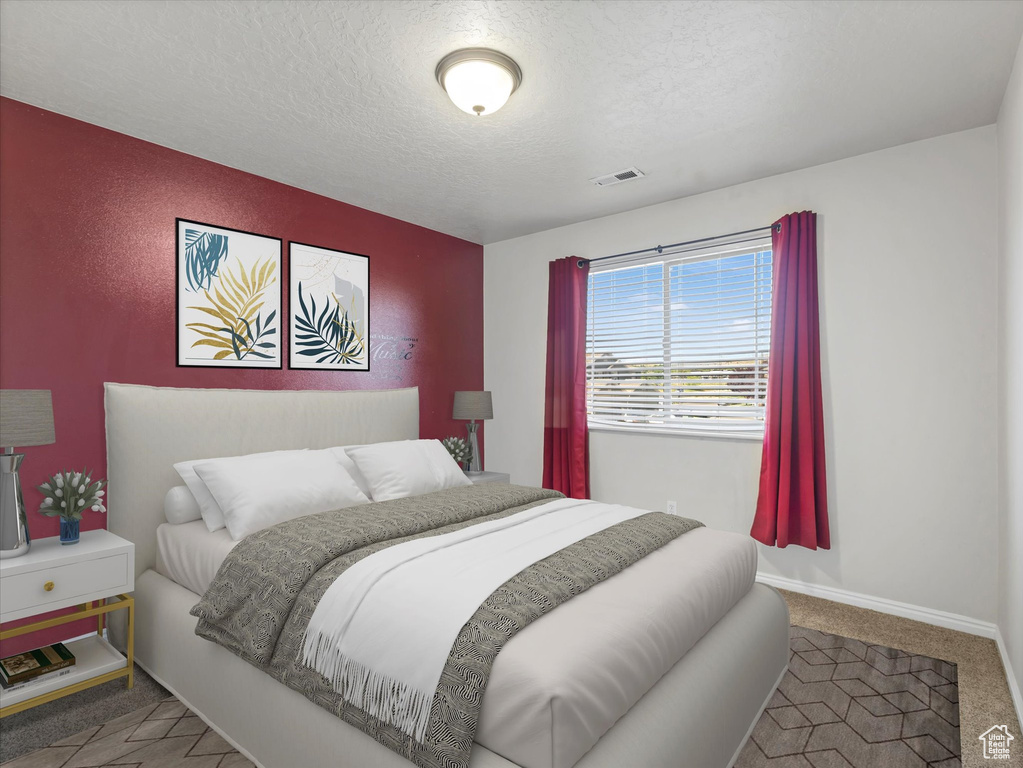 Bedroom with carpet, a textured ceiling, and baseboards