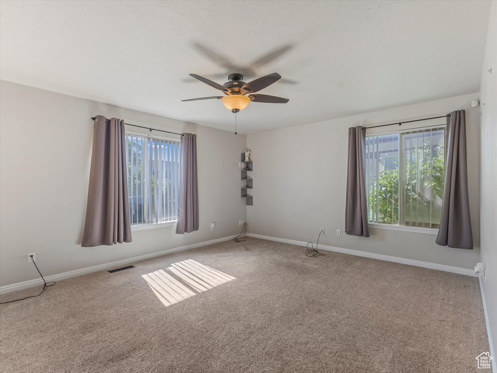 Carpeted spare room featuring ceiling fan and baseboards