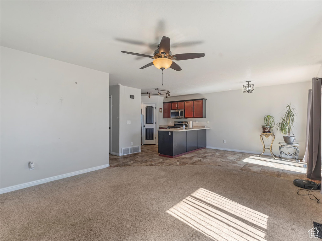 Kitchen with stainless steel microwave, open floor plan, carpet flooring, ceiling fan, and light countertops