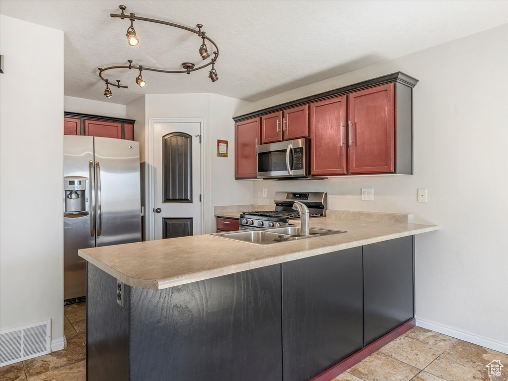 Kitchen featuring stainless steel appliances, baseboards, light countertops, and a peninsula