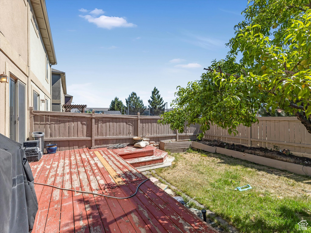 Wooden deck with a fenced backyard and a grill