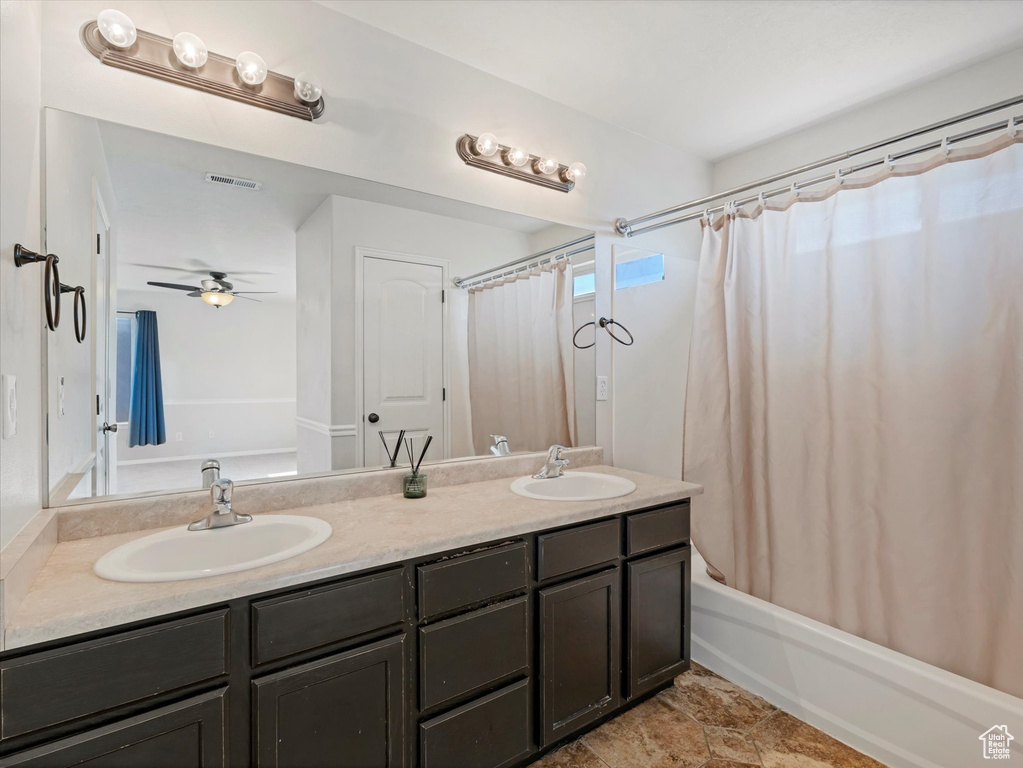 Bathroom with double vanity, shower / bath combo with shower curtain, and a ceiling fan