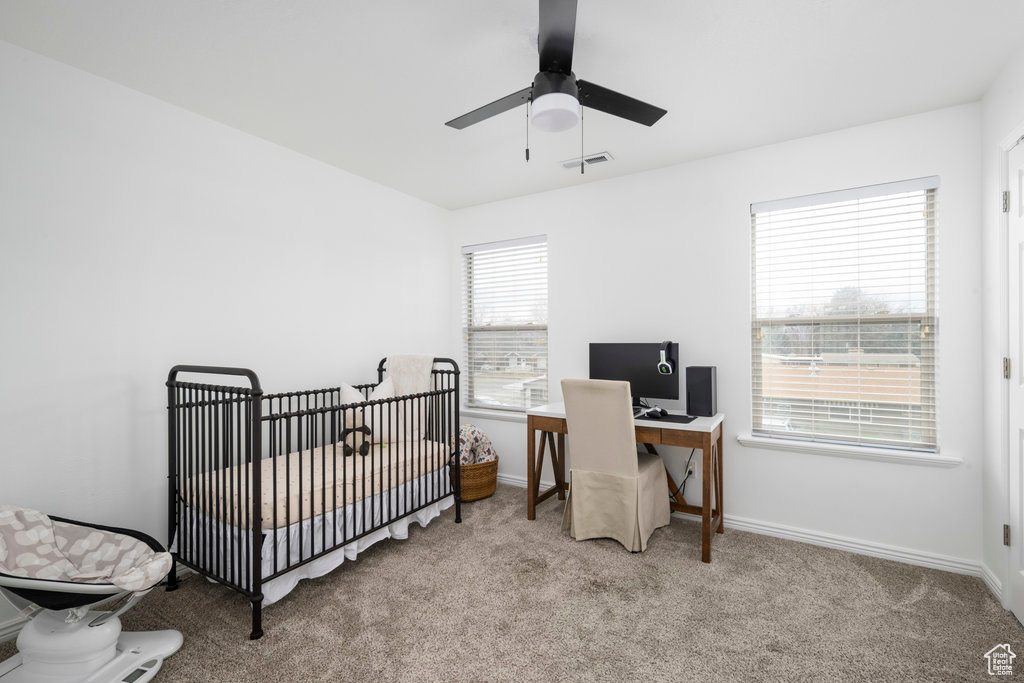 Bedroom featuring carpet flooring, a nursery area, a desk, and baseboards
