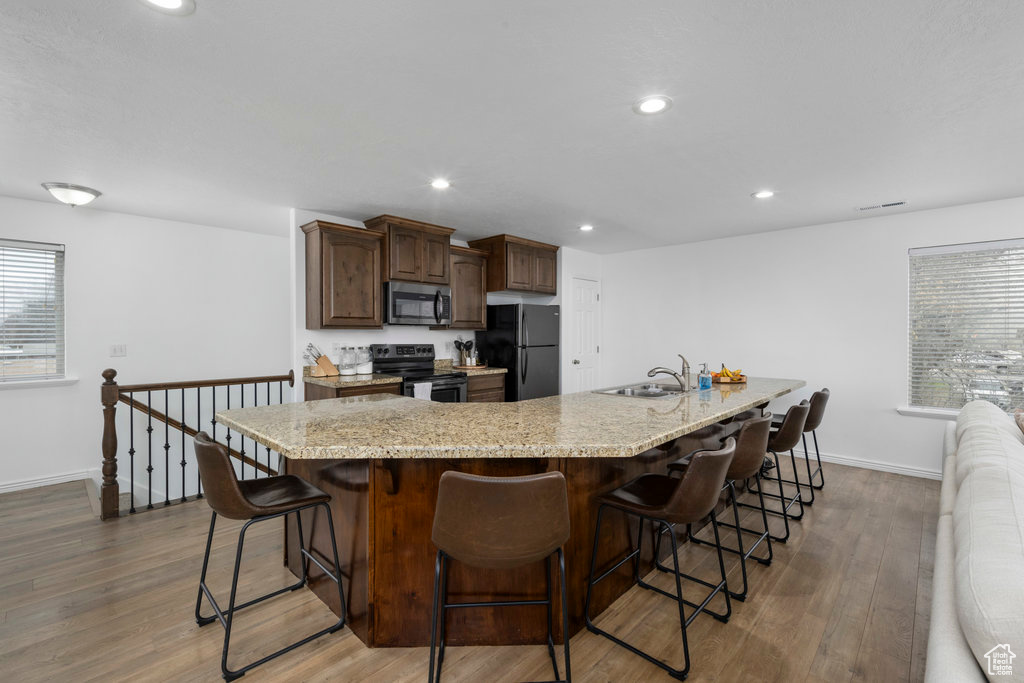 Kitchen featuring black appliances, baseboards, wood finished floors, a sink, and recessed lighting