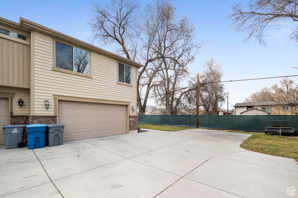 View of side of home featuring a garage, concrete driveway, and brick siding