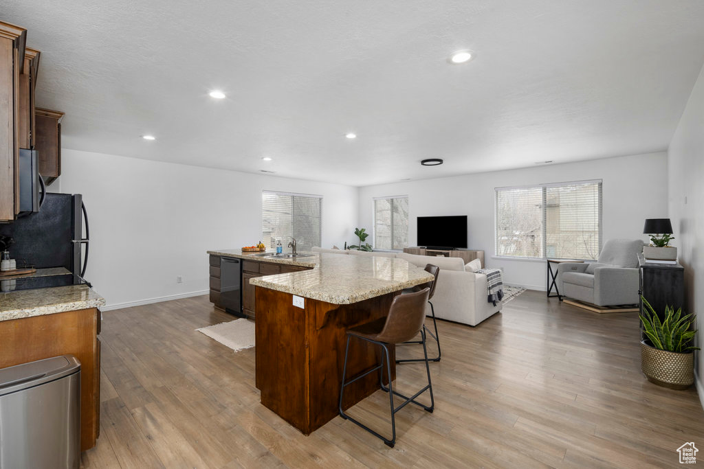 Kitchen featuring freestanding refrigerator, a large island, wood finished floors, a sink, and a breakfast bar area