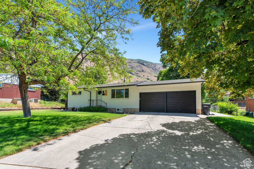 Ranch-style house with a garage, a front lawn, concrete driveway, and a mountain view