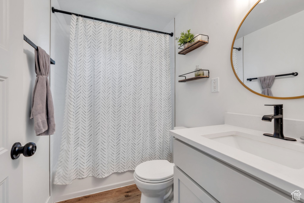 Bathroom with vanity, wood finished floors, toilet, and shower / bath combination with curtain
