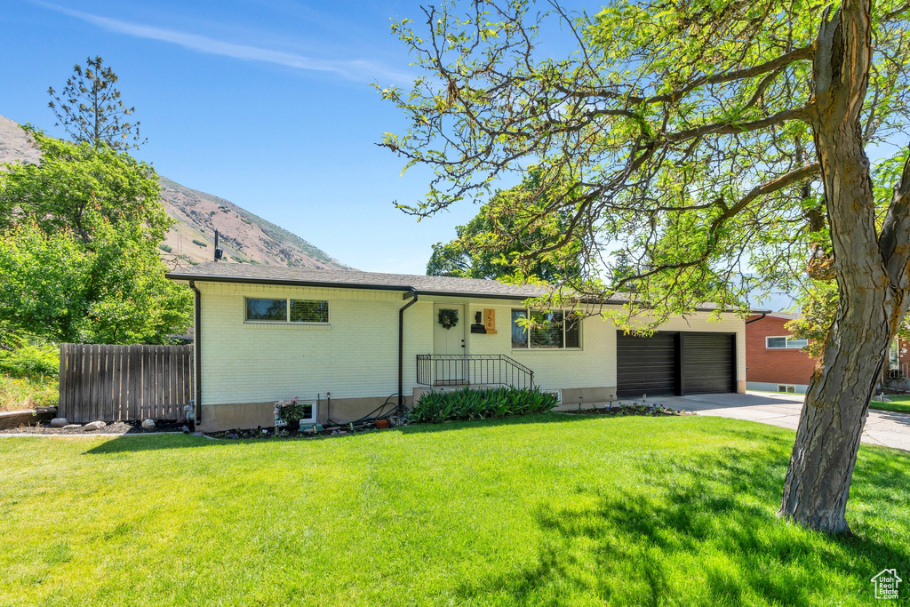 Ranch-style home with driveway, a garage, brick siding, and a mountain view