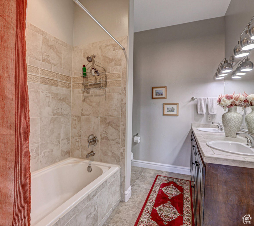 Full bath featuring tiled shower / bath, double vanity, toilet, and tile patterned flooring