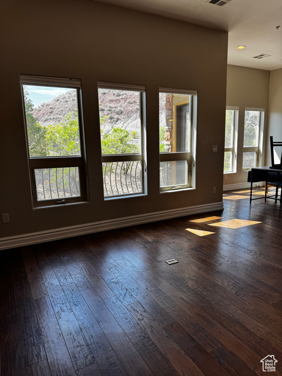 Empty room featuring dark wood-style floors and baseboards