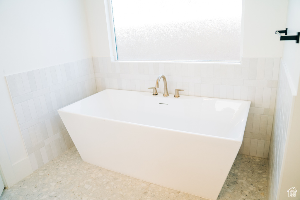 Full bathroom featuring tile walls, a freestanding bath, and wainscoting