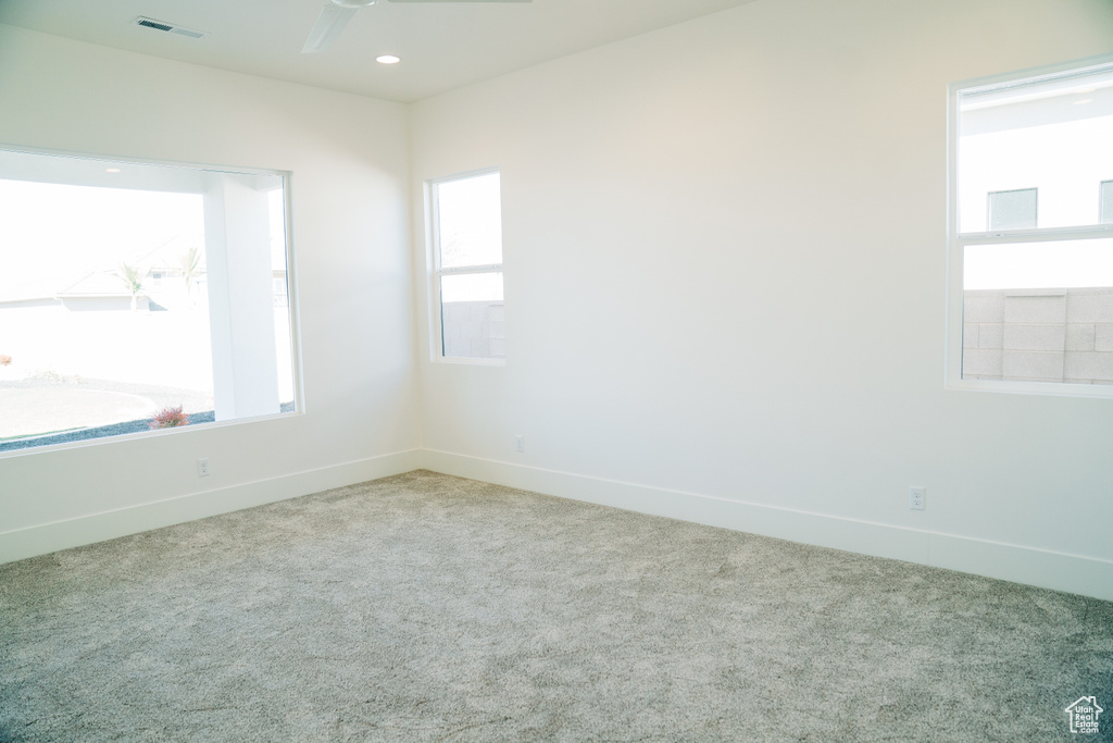 Carpeted spare room with a ceiling fan and baseboards