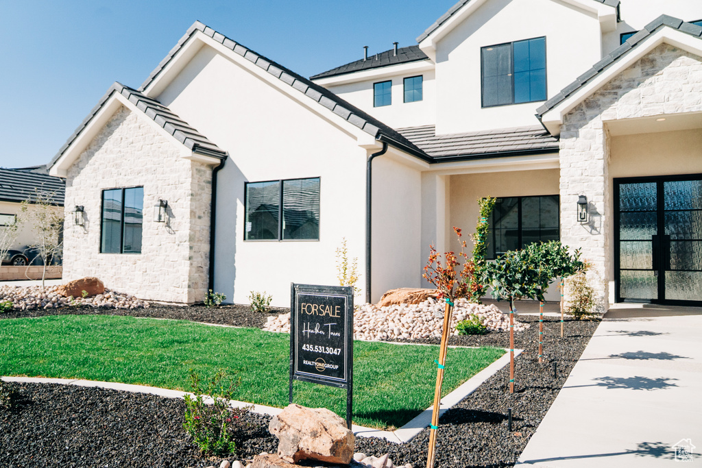 View of front of house featuring stone siding, stucco siding, a tiled roof, and a front yard