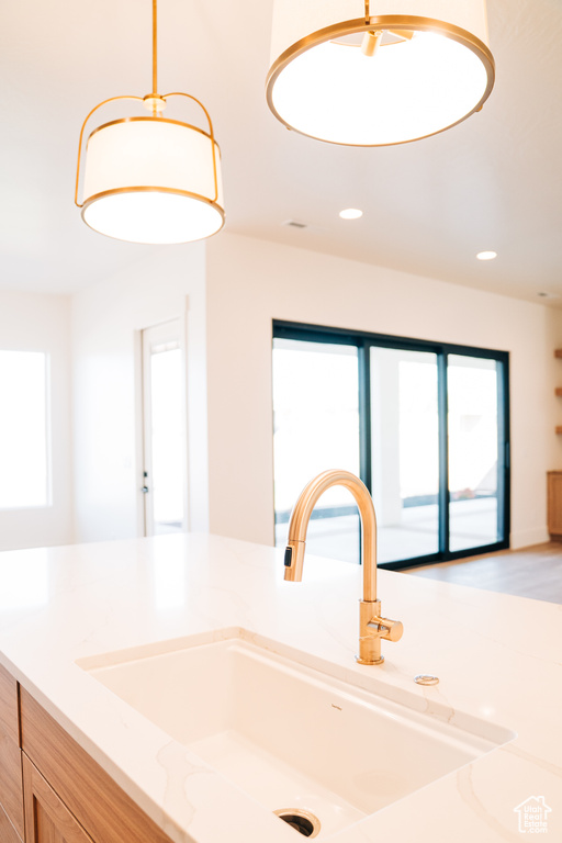 Kitchen with a sink, plenty of natural light, recessed lighting, and light stone countertops