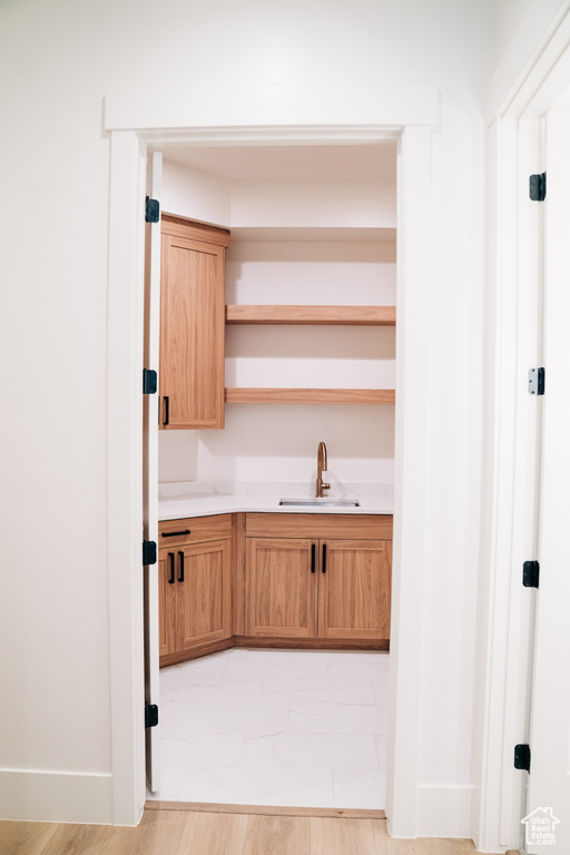 Kitchen featuring a sink, open shelves, light countertops, and baseboards