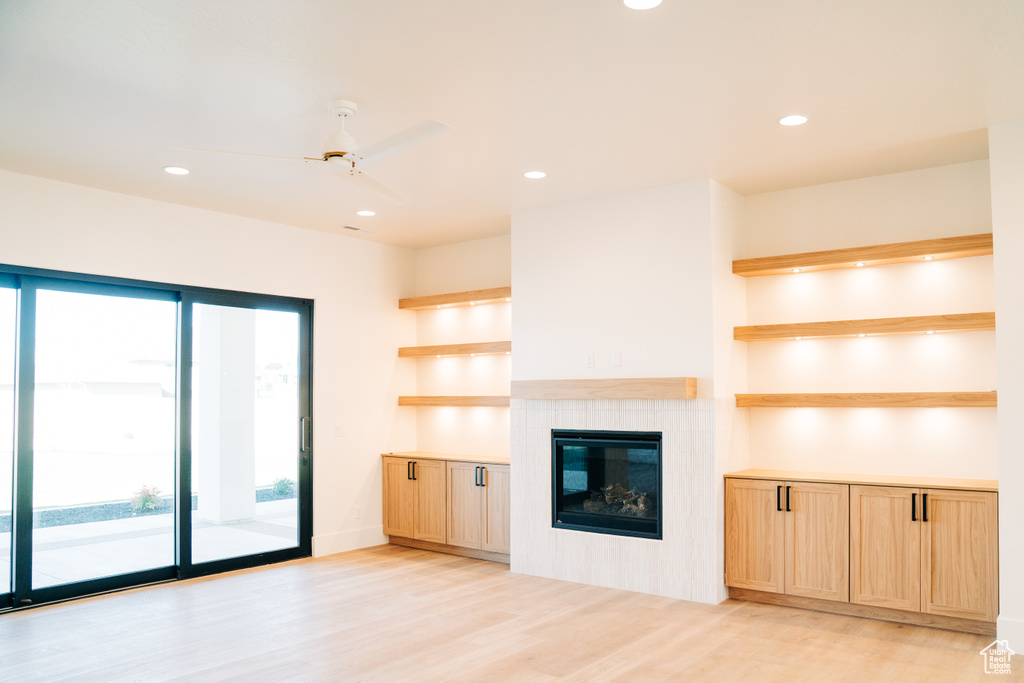 Unfurnished living room featuring recessed lighting, light wood-type flooring, a tile fireplace, and a ceiling fan
