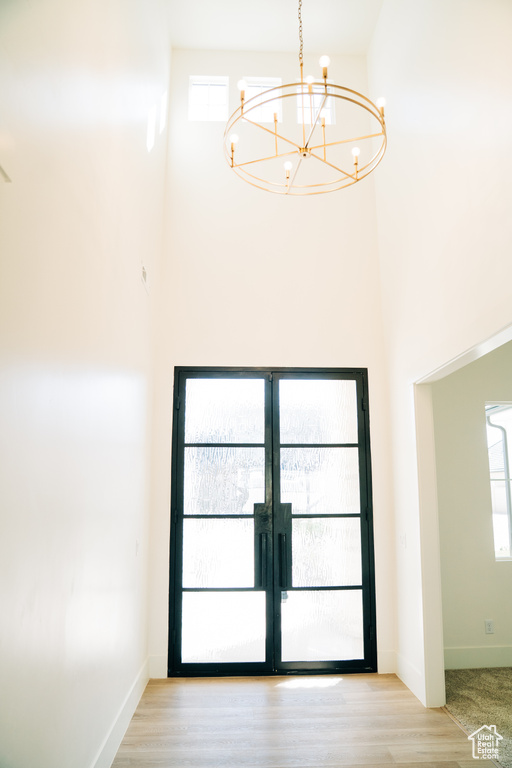 Detailed view of a chandelier, french doors, baseboards, and wood finished floors