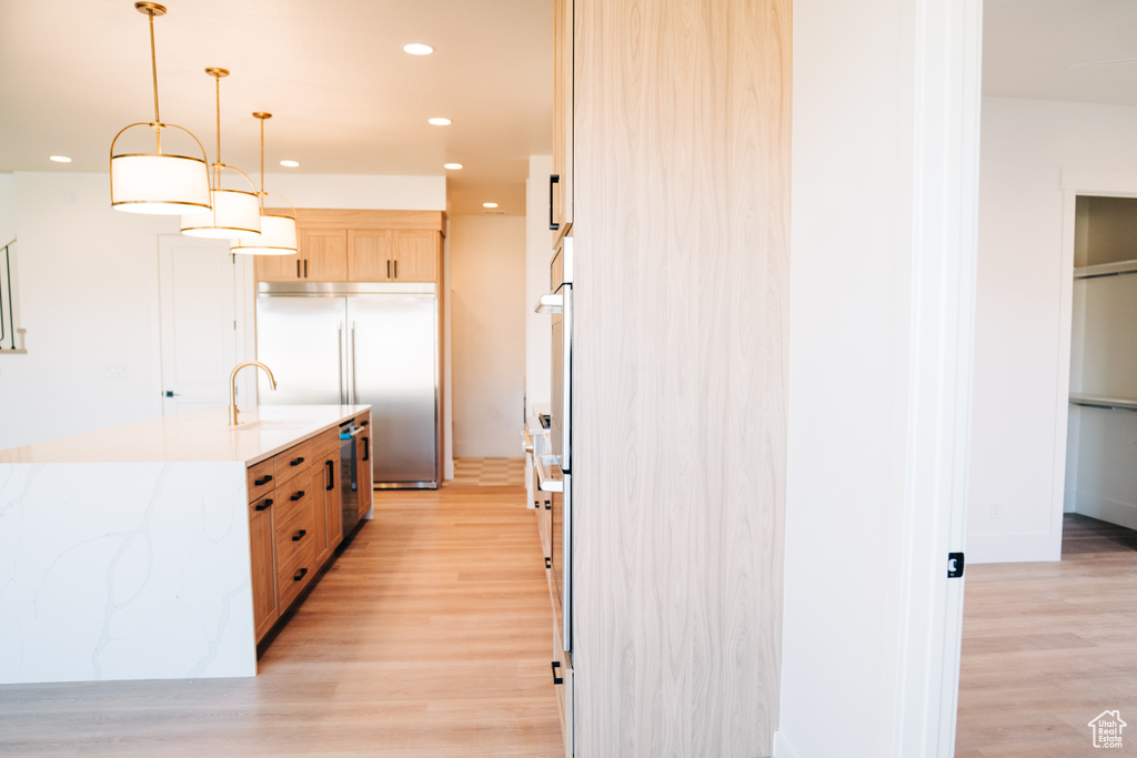 Kitchen featuring stainless steel built in refrigerator, light wood-style floors, light brown cabinets, oven, and recessed lighting