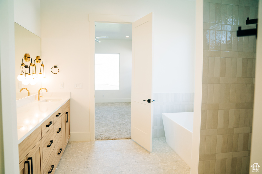 Bathroom featuring double vanity, a freestanding tub, and a ceiling fan