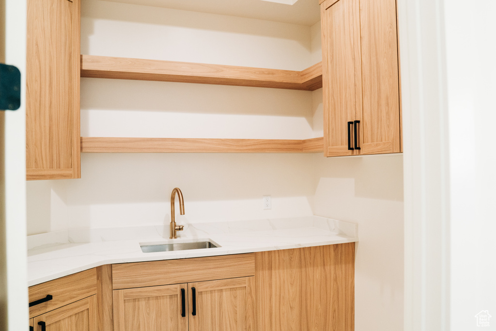 Kitchen with open shelves, a sink, and light brown cabinets