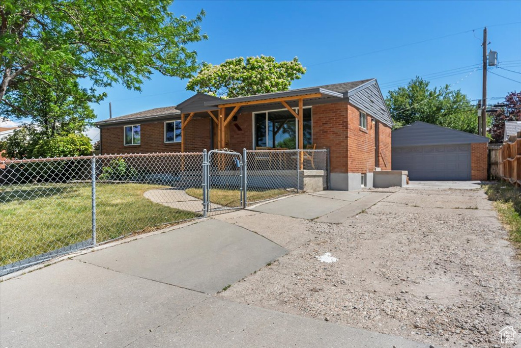 Ranch-style house with brick siding, a gate, a detached garage, covered porch, and an outbuilding