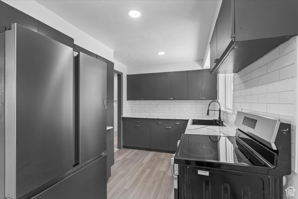 Kitchen featuring stainless steel appliances, a sink, tasteful backsplash, recessed lighting, and light wood-style floors
