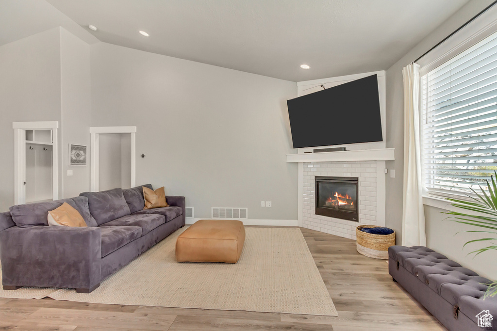 Living room with wood finished floors, a brick fireplace, healthy amount of natural light, recessed lighting, and baseboards