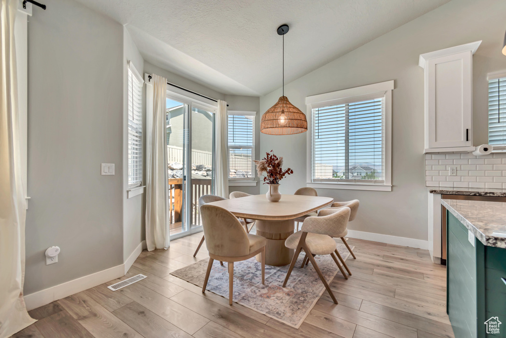 Dining area featuring baseboards, vaulted ceiling, and light wood-style flooring