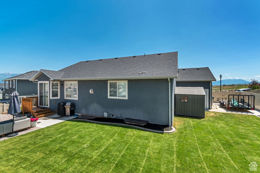 Back of property featuring a patio, a mountain view, roof with shingles, and stucco siding