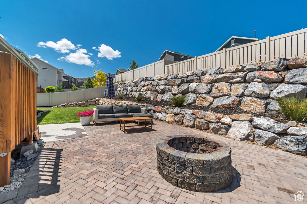 Fenced backyard featuring a patio and an outdoor living space with a fire pit