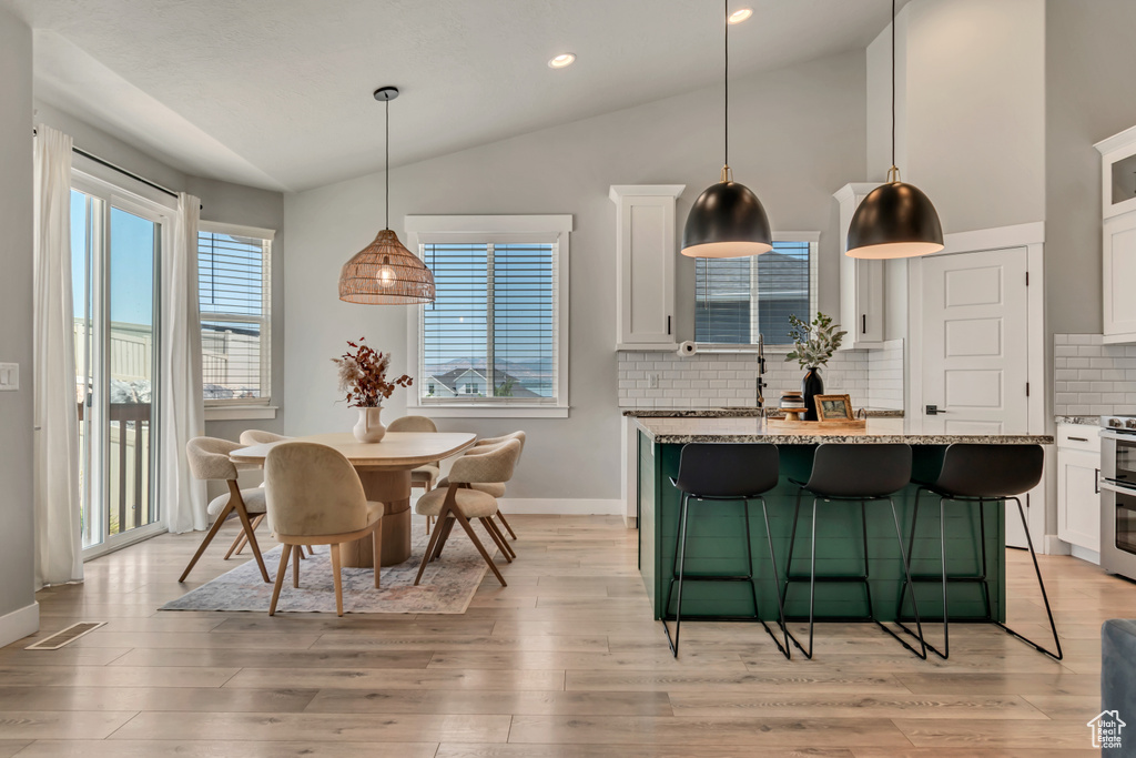 Dining space featuring lofted ceiling, light wood-style floors, baseboards, and recessed lighting