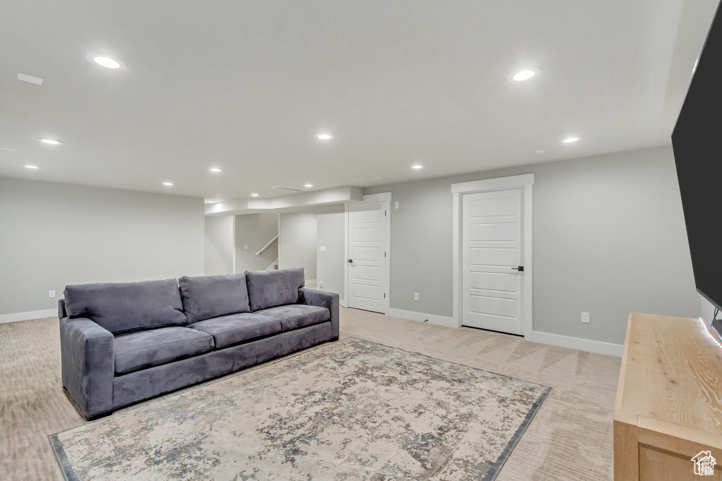 Living area featuring recessed lighting, baseboards, light carpet, and stairway