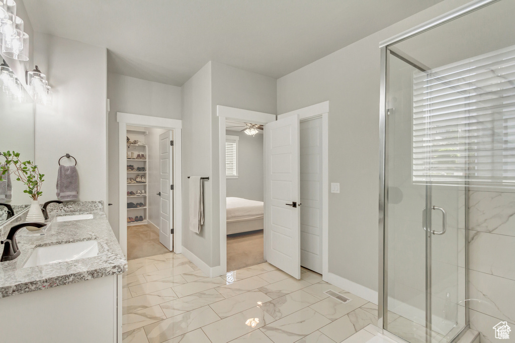 Bathroom featuring double vanity, a stall shower, marble finish floors, ensuite bathroom, and a ceiling fan