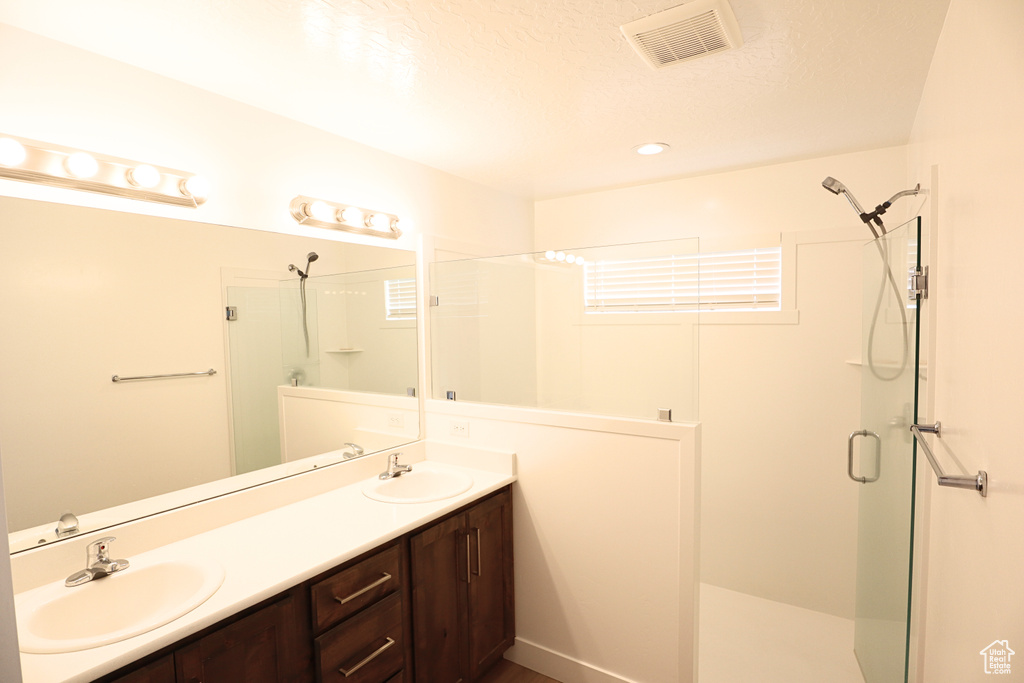 Full bathroom featuring a shower stall and double vanity