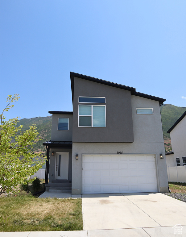 Contemporary house with an attached garage, stucco siding, concrete driveway, a standing seam roof, and metal roof
