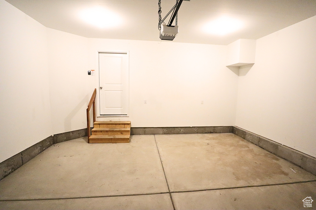 Garage featuring a garage door opener and baseboards