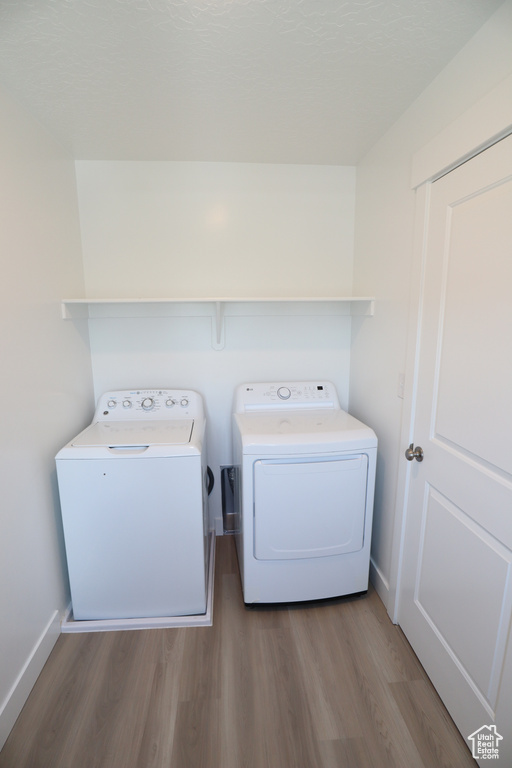 Laundry area with washer and clothes dryer, wood finished floors, and baseboards