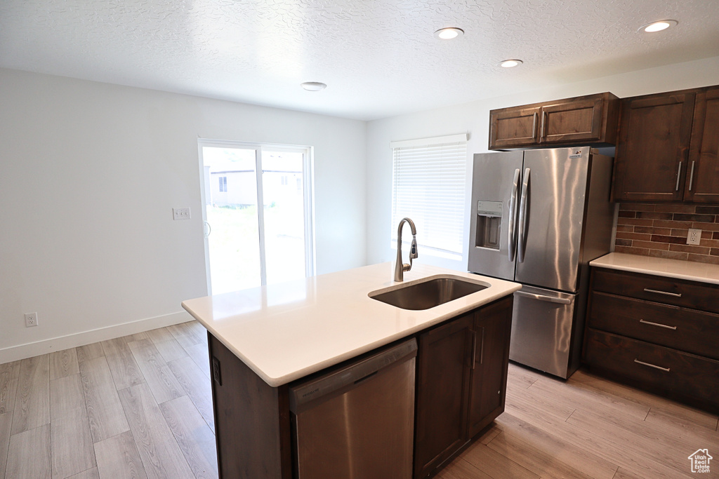 Kitchen featuring appliances with stainless steel finishes, a sink, light wood finished floors, light countertops, and recessed lighting