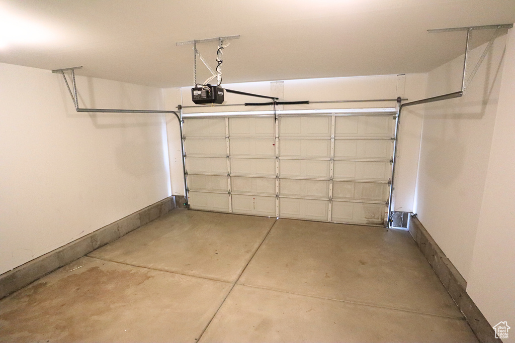Garage featuring a garage door opener and baseboards