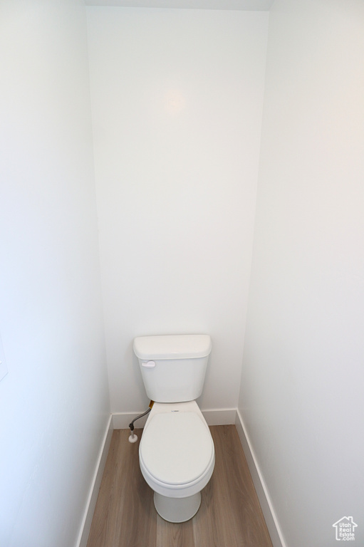 Bathroom with wood finished floors, baseboards, and toilet