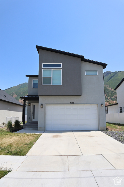 Modern home featuring a garage, a mountain view, stucco siding, and concrete driveway